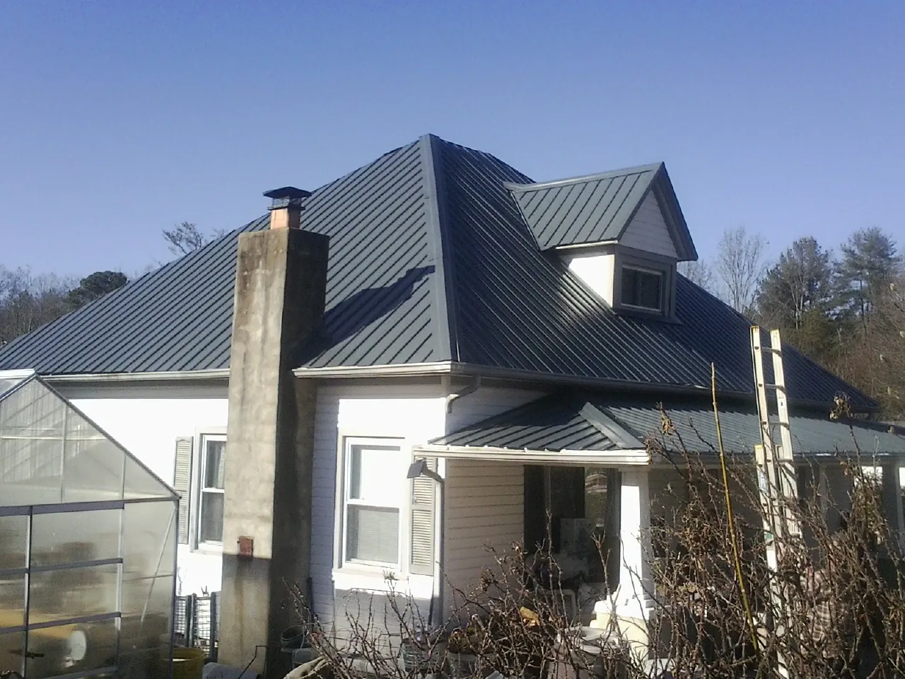 Dark blue standing seam metal roof on a white farmhouse with dormer — Slate & Tile Roof Repair by Roofing Brothers in Convent Station