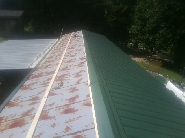Old rusted panels beside newly installed green metal roofing — Wind Damage Roof Repair by Roofing Brothers in Convent Station