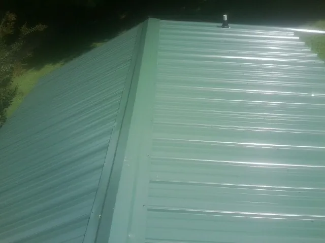 New green metal panels meeting at the ridge of a roof — Flat Roof Repair work by our crew in Convent Station