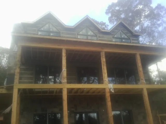 Dormers and porch framing on a large log home under construction — Roof Coating work by our crew in Convent Station