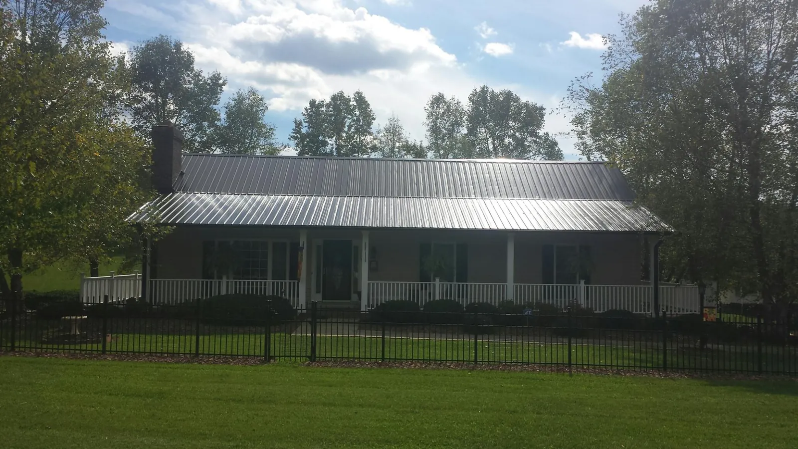 Gray metal roof on a brick ranch with a full width front porch — Gutter Guard Installation work by our crew in Convent Station