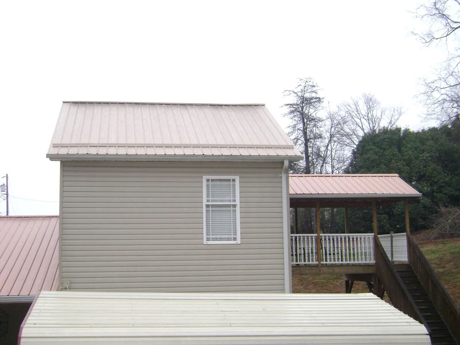 Tan metal roofs on a two story addition and attached porch, from a Roof Replacement job in Convent Station