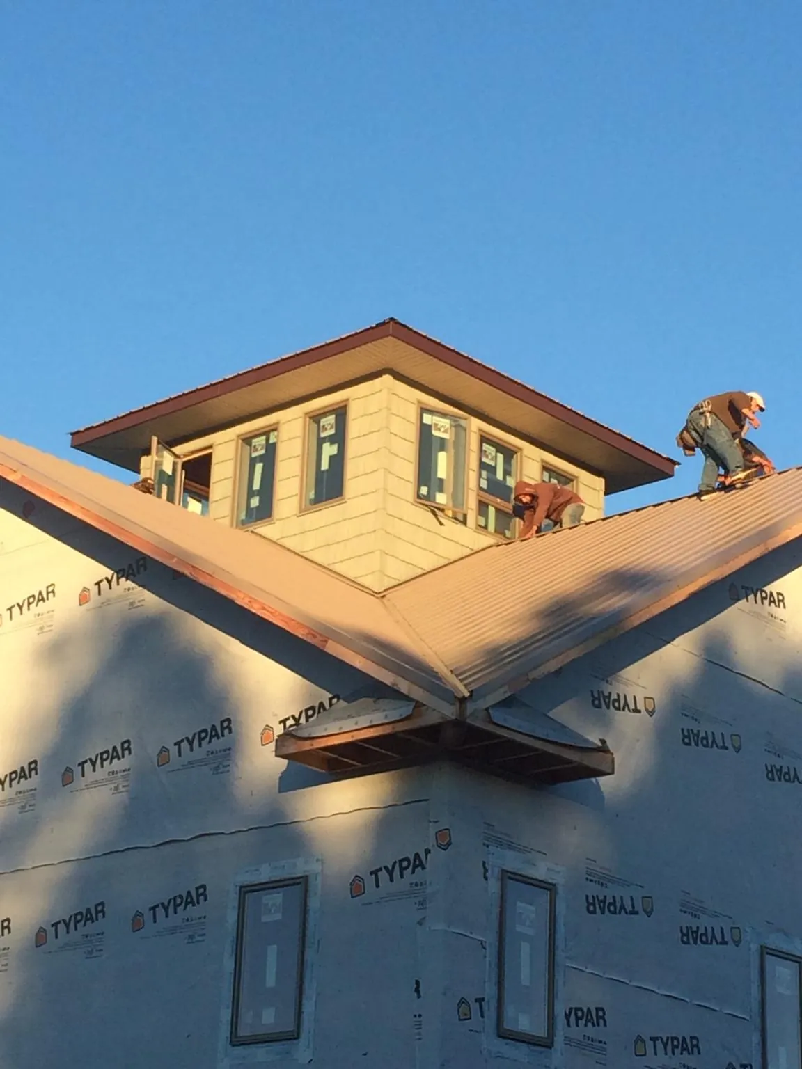 Roofers working around a rooftop cupola on a new metal roof at sunset — Roof Waterproofing in Convent Station by Roofing Brothers